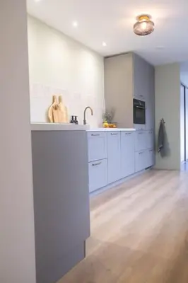 a large kitchen with white cabinets and a sink at Julia's Holidayhome in Egmond-Binnen