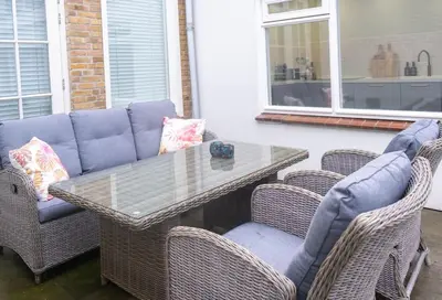 a wicker table and two chairs with a glass table and a table and chairs at Julia's Holidayhome in Egmond-Binnen