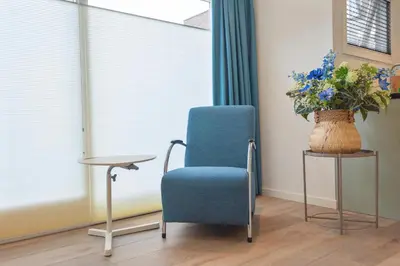 a blue chair sitting next to a table with a vase of flowers at Blue Oasis Cottage - Free Parking in Zandvoort