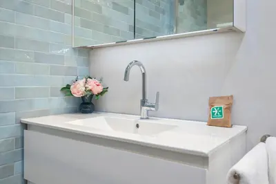 a white sink in a bathroom with a vase of flowers at Blue Oasis Cottage - Free Parking in Zandvoort