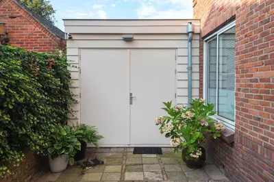 a white garage door on a brick building at Blue Oasis Cottage - Free Parking in Zandvoort