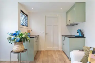 a kitchen and living room with a vase of blue flowers at Blue Oasis Cottage - Free Parking in Zandvoort