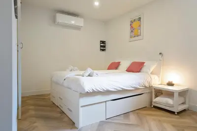 a white bedroom with a bed and a night stand at Skua Escape in Zandvoort