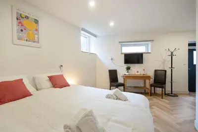 a bedroom with a large white bed and a desk at Skua Escape in Zandvoort