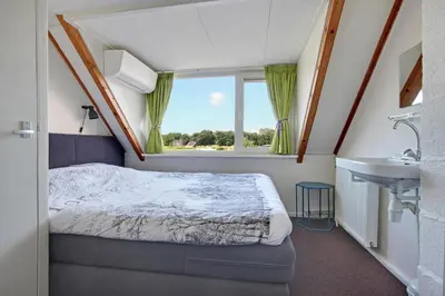 a small bedroom with a bed and a sink at Vakantiehuis de Creutz in Beverwijk