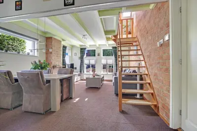 a room with a brick wall and a wooden ladder at Vakantiehuis de Creutz in Beverwijk