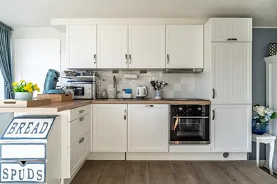 a white kitchen with white cabinets and appliances at Huisje Bloemenzee in Noordwijkerhout