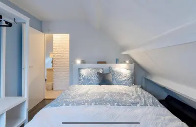 a bedroom with a large bed with blue walls at Huisje Bloemenzee in Noordwijkerhout