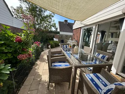 a patio with a table and chairs and flowers at Huisje Bloemenzee in Noordwijkerhout
