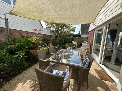 a patio with a table and chairs under an umbrella at Huisje Bloemenzee in Noordwijkerhout