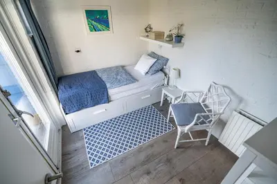 a small room with a bed and a chair at Huisje Bloemenzee in Noordwijkerhout