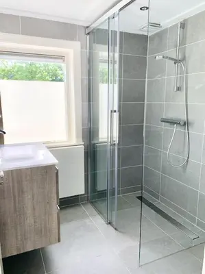 a bathroom with a glass shower with a sink at Charming villa,central location,train and bus nearby in Soest