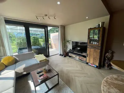 a living room with a white couch and a television at Luxe appartement bij Zuidas met tuin en buitendouche in Amsterdam