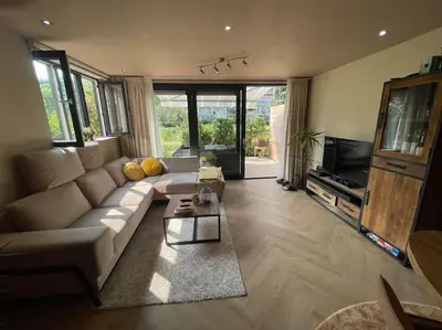a living room with a couch and a tv at Luxe appartement bij Zuidas met tuin en buitendouche in Amsterdam