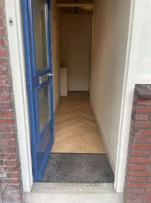 an empty hallway with a blue door and a room at Luxe appartement bij Zuidas met tuin en buitendouche in Amsterdam