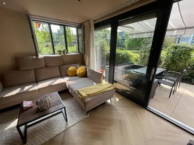a living room with a couch and a table at Luxe appartement bij Zuidas met tuin en buitendouche in Amsterdam