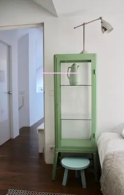 a green chair sitting next to a bed with a lamp at Private room in Design House near Amsterdam in Halfweg
