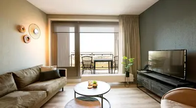 a living room with a couch and a tv and a table at Lido Zeezicht appartementen in Egmond aan Zee