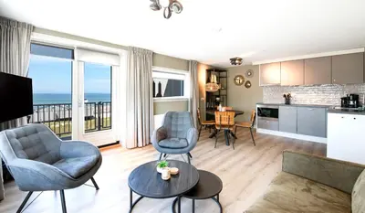 a kitchen and living room with a view of the ocean at Lido Zeezicht appartementen in Egmond aan Zee