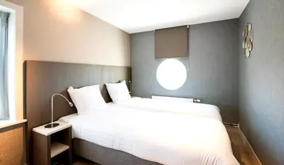 a bedroom with a white bed and a window at Lido Zeezicht appartementen in Egmond aan Zee