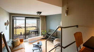 a living room with a view of a balcony at Lido Zeezicht appartementen in Egmond aan Zee