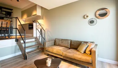 a living room with a couch and a staircase at Lido Zeezicht appartementen in Egmond aan Zee