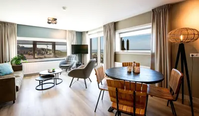 a living room with a table and chairs and a couch at Lido Zeezicht appartementen in Egmond aan Zee