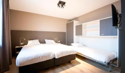 a bedroom with two beds and a flat screen tv at Lido Zeezicht appartementen in Egmond aan Zee