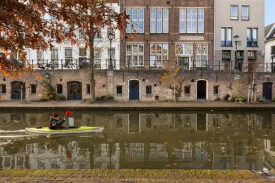 a person in a boat on the water in front of a building at Luxurious renovated apartment in Utrecht City center with view on the old canal in Utrecht