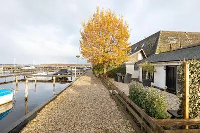 a marina with a house and a wooden fence at Woonboot De Rietpieper in Loosdrecht