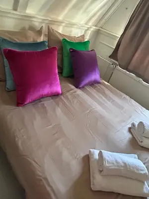 a large white bed with purple and green pillows at Cosy by Mandy in Amsterdam