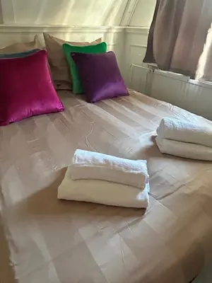 three towels on a bed with purple and green pillows at Cosy by Mandy in Amsterdam