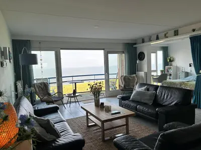 a living room with a couch and a table at Appartement Atlantis met Zeezicht in Egmond aan Zee