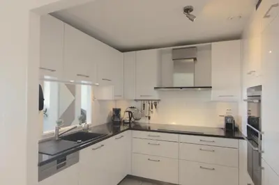 a white kitchen with white cabinets and a sink at Appartement Atlantis met Zeezicht in Egmond aan Zee