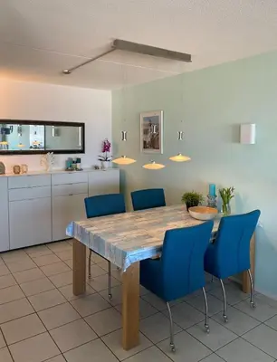 a kitchen with a wooden table and blue chairs at Appartement Atlantis met Zeezicht in Egmond aan Zee