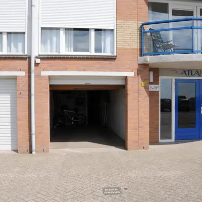 a brick building with a garage with a bike in it at Appartement Atlantis met Zeezicht in Egmond aan Zee