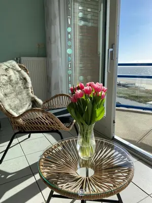 a vase of pink tulips sitting on a glass table at Appartement Atlantis met Zeezicht in Egmond aan Zee