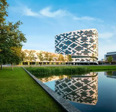 a building with its reflection in a body of water at Hilton Amsterdam Airport Schiphol in Schiphol