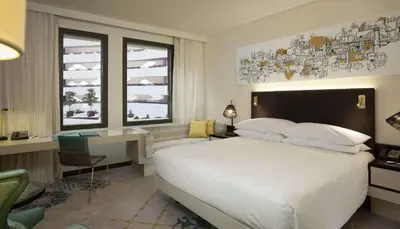 a hotel room with a bed and a desk and windows at Hilton Amsterdam Airport Schiphol in Schiphol