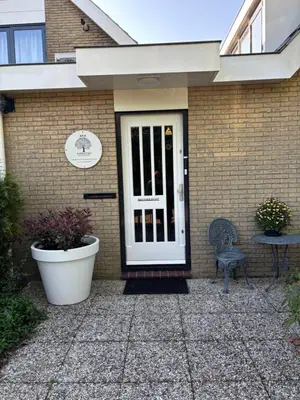 a brick house with a white door and a chair at Parkzicht Zwanenburg in Zwanenburg