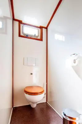 a bathroom with a toilet with a wooden toilet seat at Tjalkjacht Pelikaan Hoorn in Hoorn