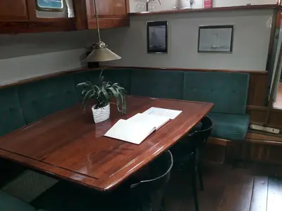 a wooden table in a restaurant with a potted plant on it at Tjalkjacht Pelikaan Hoorn in Hoorn