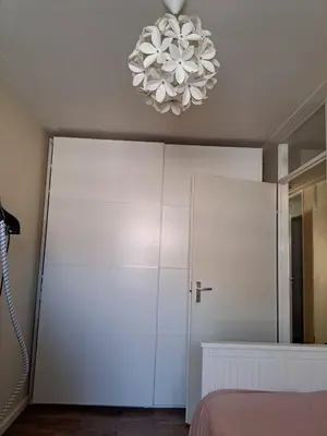 a bedroom with a white closet and a chandelier at Cosy Apartment in Hilversum in Hilversum