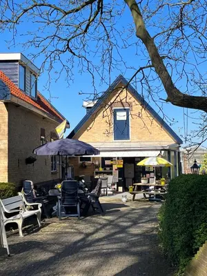 a group of chairs and tables in front of a building at B&B Dol - Fijn in Benningbroek