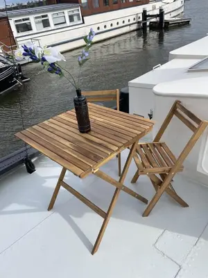 a wooden table and a vase with flowers on a boat at Forecastle KL in Amsterdam