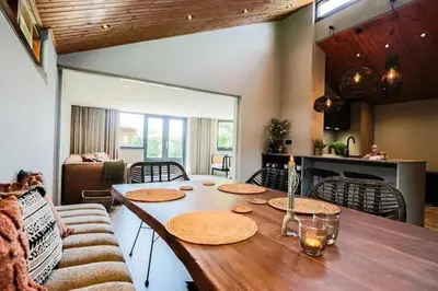 a living room with a wooden table and a kitchen at Dune Lagoon in Egmond aan den Hoef
