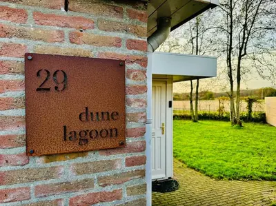 a sign on the side of a brick building at Dune Lagoon in Egmond aan den Hoef