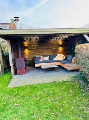 a patio with a blue couch and a table at Dune Lagoon in Egmond aan den Hoef