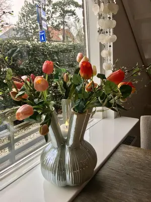 a silver vase filled with flowers sitting on a table at Vakantiehuis De Zeeparel in Zandvoort