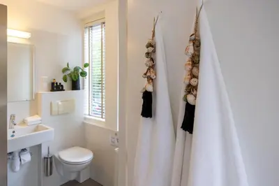 a bathroom with a toilet and a white shower curtain at Vakantiehuis De Zeeparel in Zandvoort